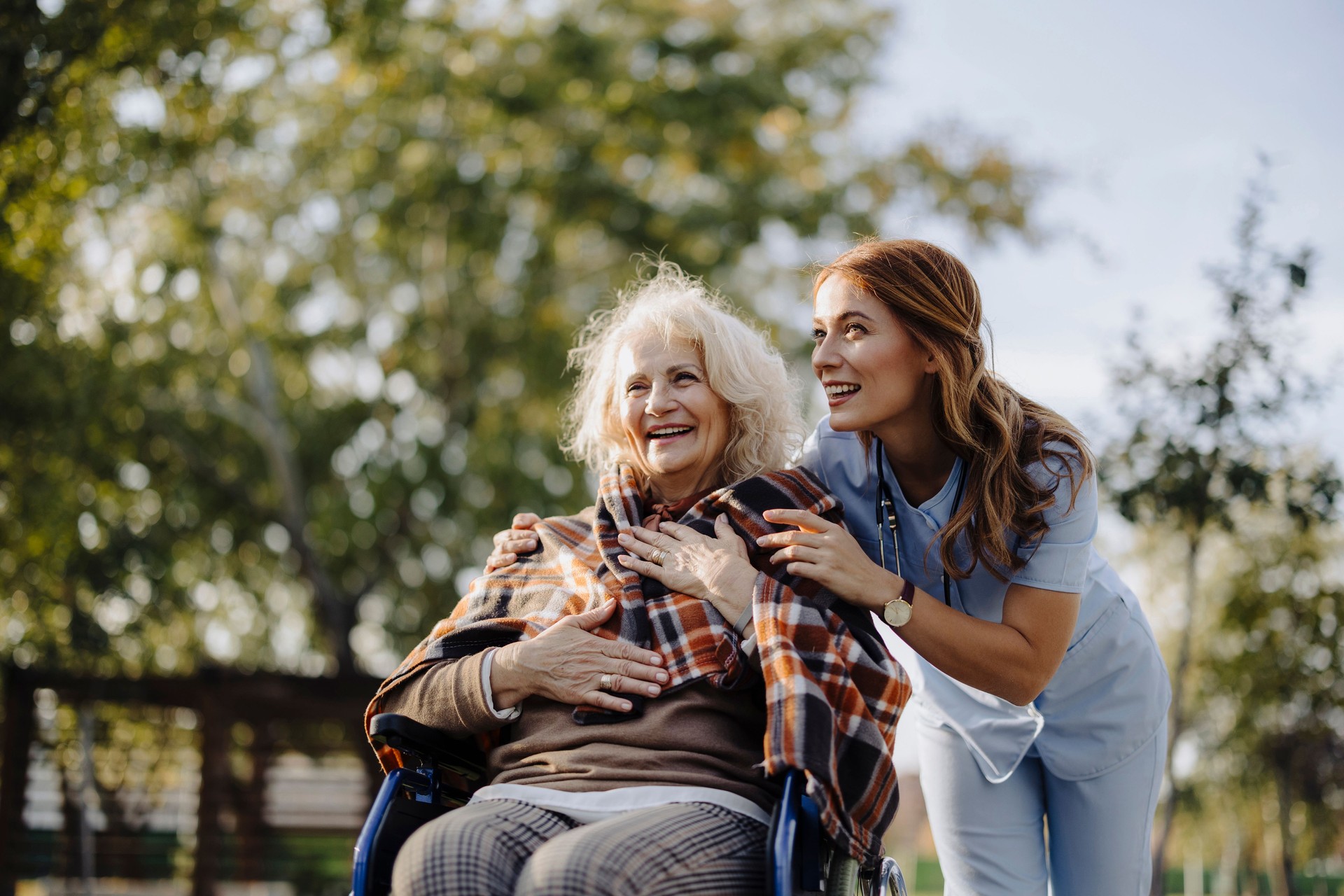 Shot of an elderly woman in a wheelchair being covered with blanket by a nurse