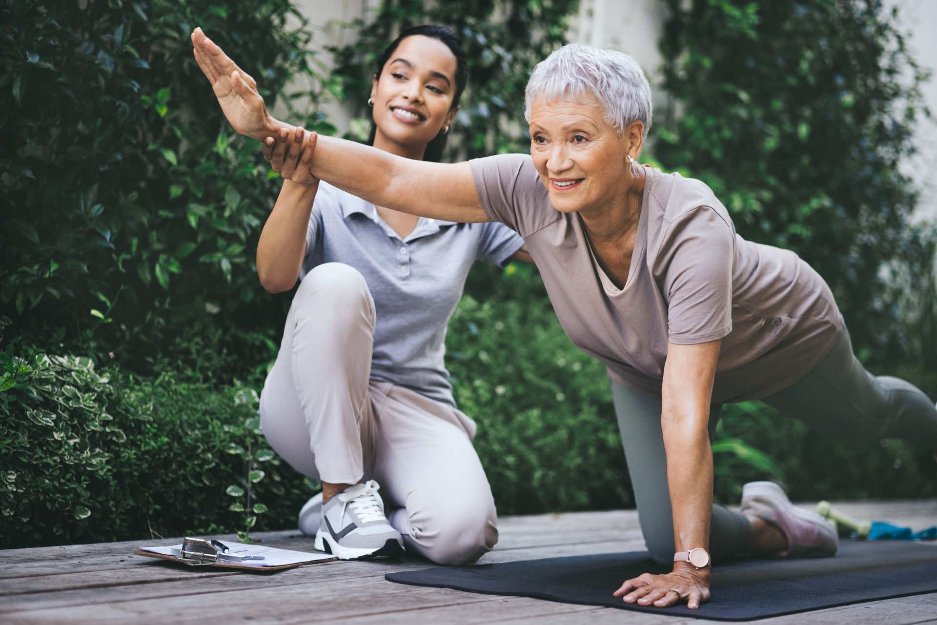 Shot of an older woman doing light floor exercises during a session with a physiotherapist outside
