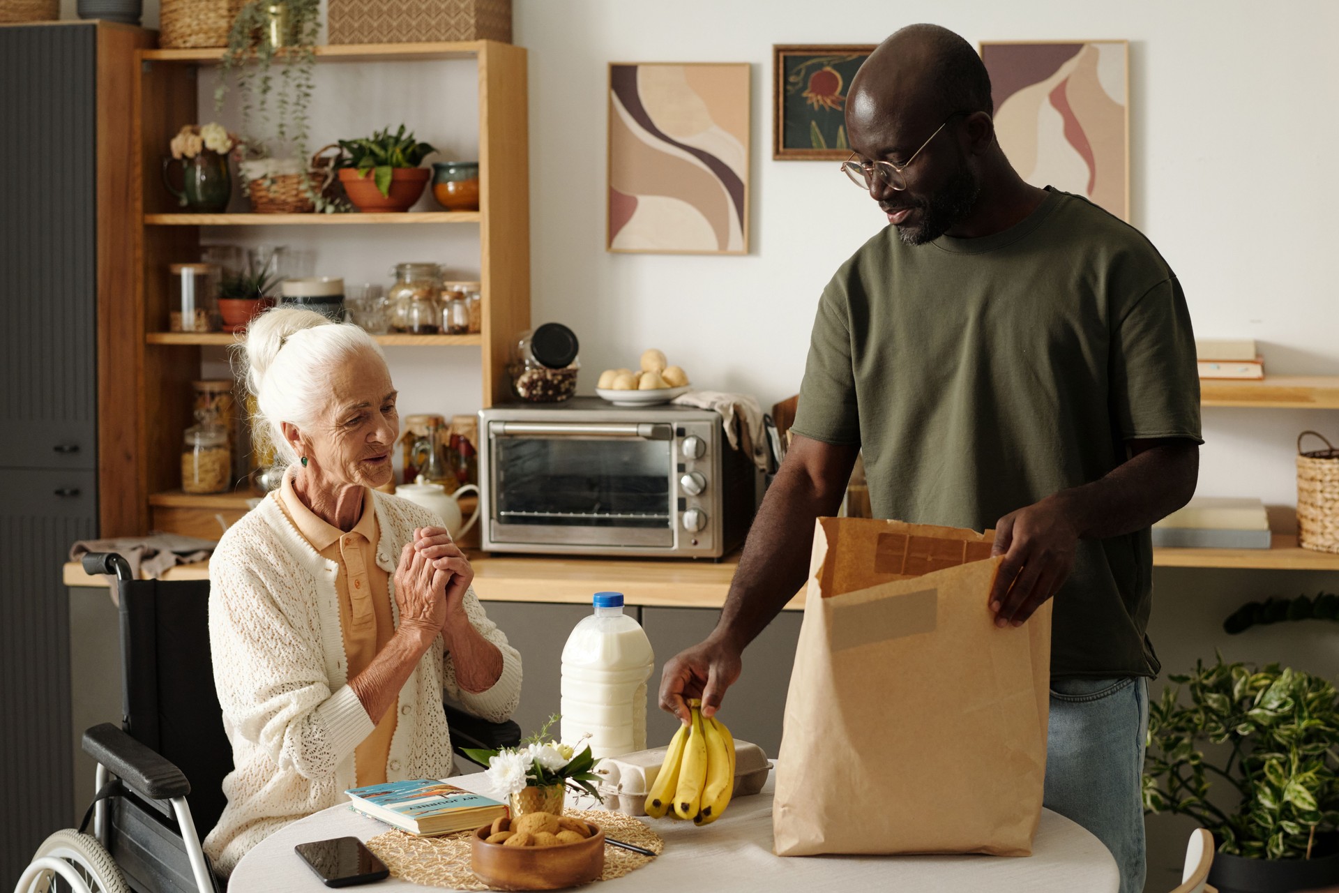 Black Man Assisting Senior Caucasian Woman with Disability at Home
